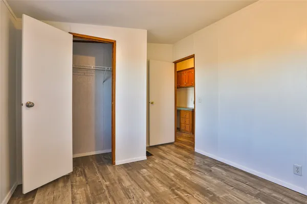 a view of an empty room with closet and wooden floor