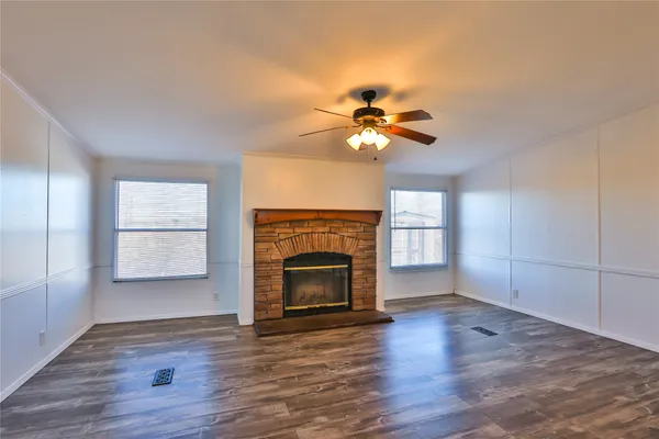 an empty room with windows fireplace and wooden floor