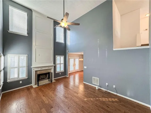 a view of a livingroom with wooden floor a ceiling fan and windows