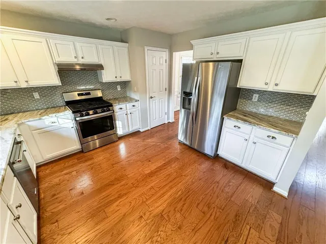 a kitchen with granite countertop a refrigerator stove and sink