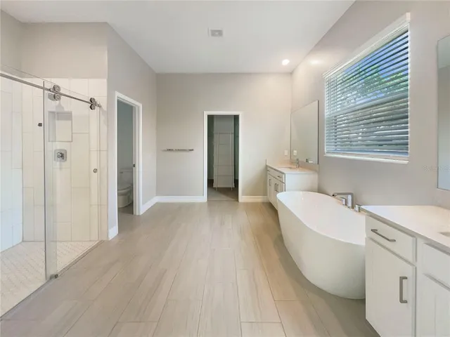 a bathroom with a bathtub a double vanity sink and mirror