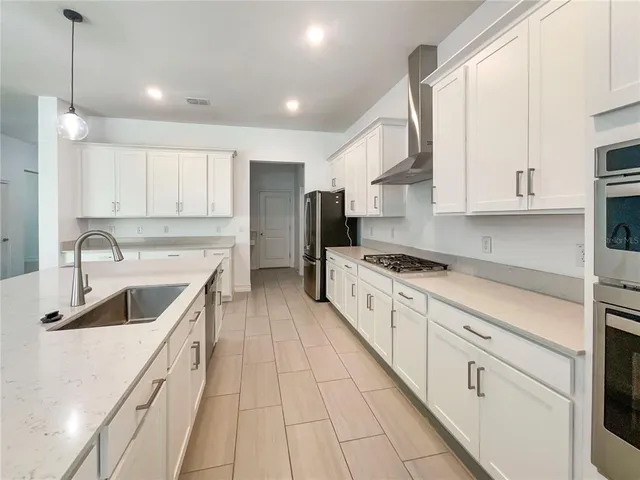 a kitchen with stainless steel appliances sink a stove and white cabinets