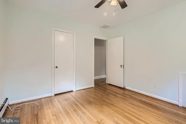 an empty room with ceiling fan and wooden floor