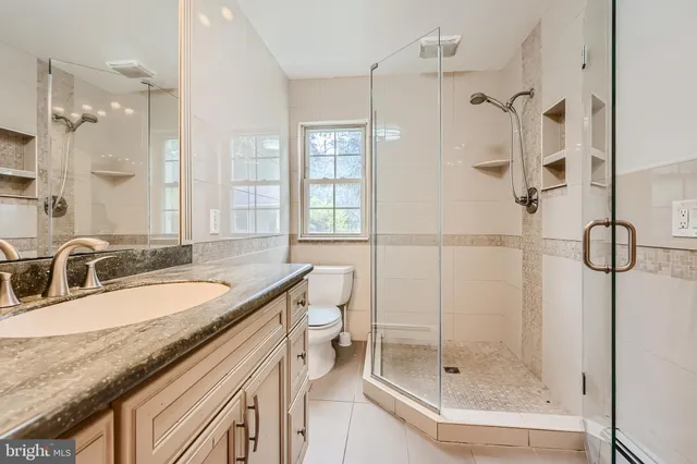 a bathroom with a granite countertop sink a toilet and shower