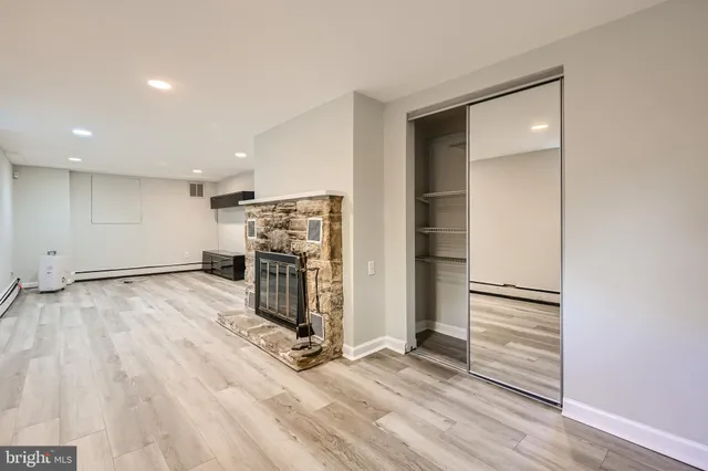 an empty room with wooden floor closet and windows