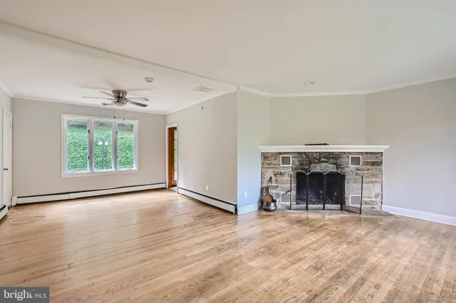an empty room with wooden floor fireplace and windows