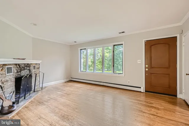 an empty room with fireplace cabinet and windows