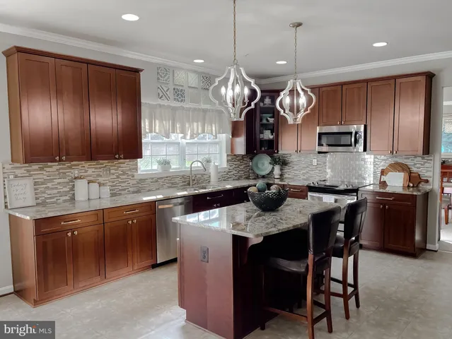 a large kitchen with kitchen island a island a sink a counter and stainless steel appliances