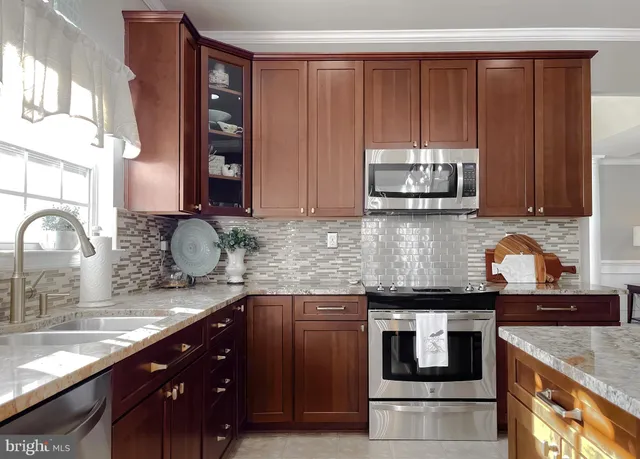 a kitchen with stainless steel appliances granite countertop wooden cabinets a stove and a sink