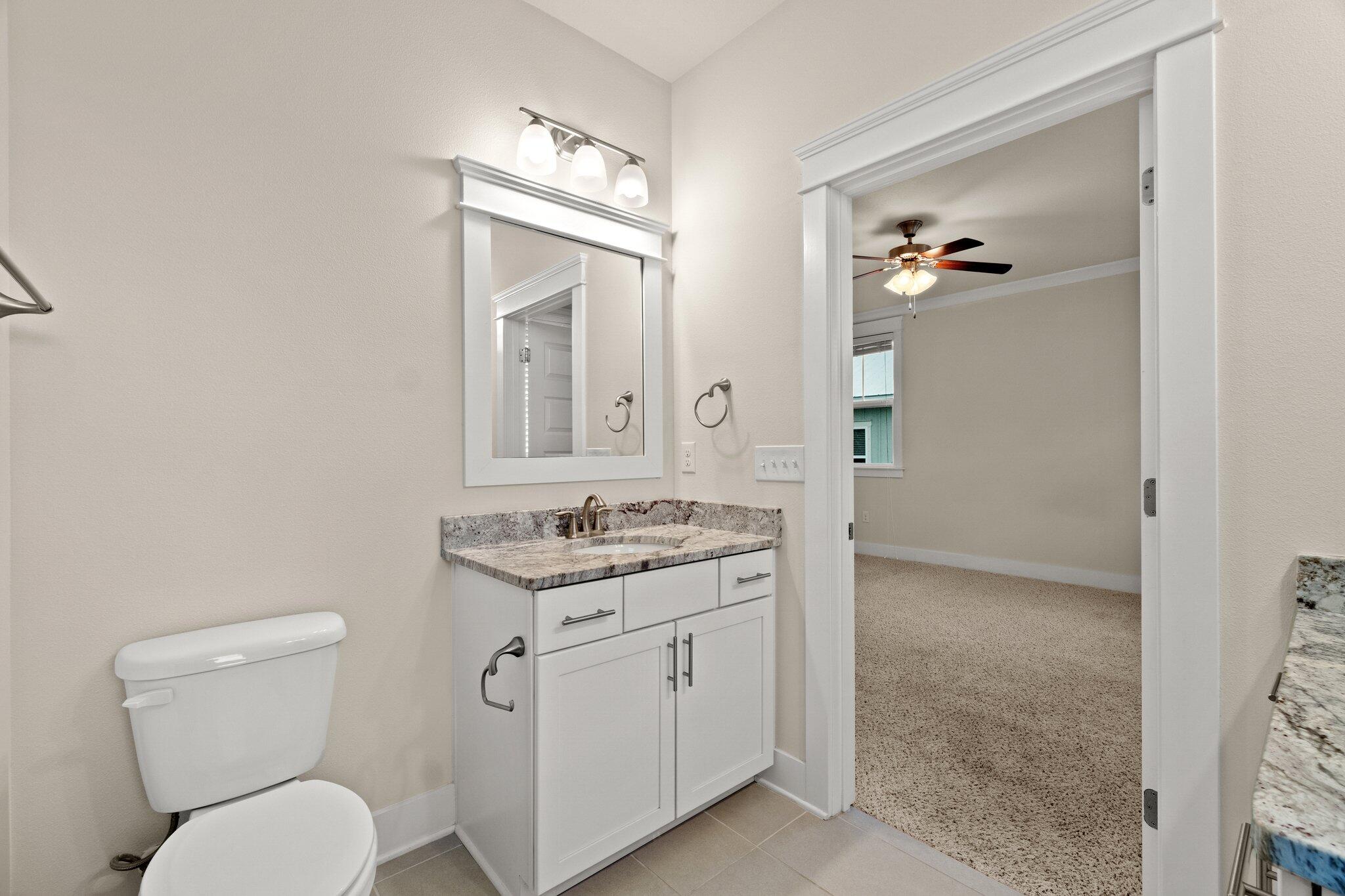 99 Grande Pointe Circle Inlet Beach, FL 32461 - Photo 25 of 34 a bathroom with a granite countertop toilet a sink and a mirror