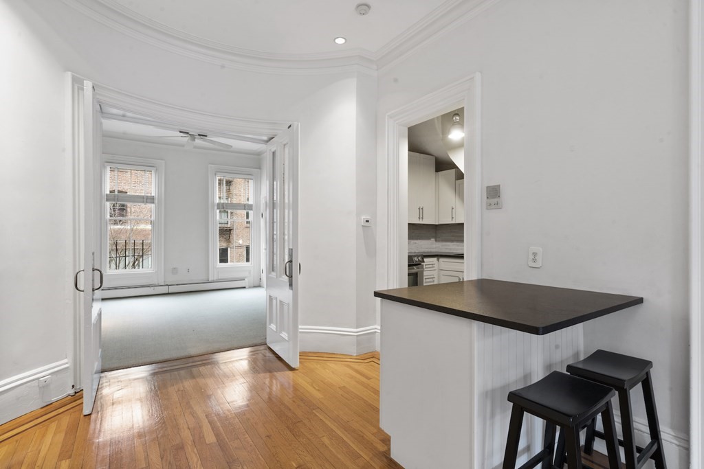 103 Appleton Street, Unit 3 Boston, MA 02116 - Photo 6 of 11 a view of a kitchen and an empty room with wooden floor and kitchen view