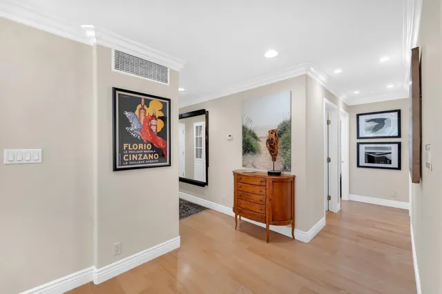 a kitchen with stainless steel appliances kitchen island granite countertop a refrigerator a oven and white cabinets with wooden floors