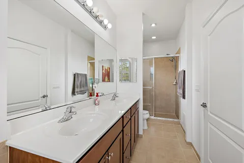a spacious bathroom with a sink a shower a mirror and vanity