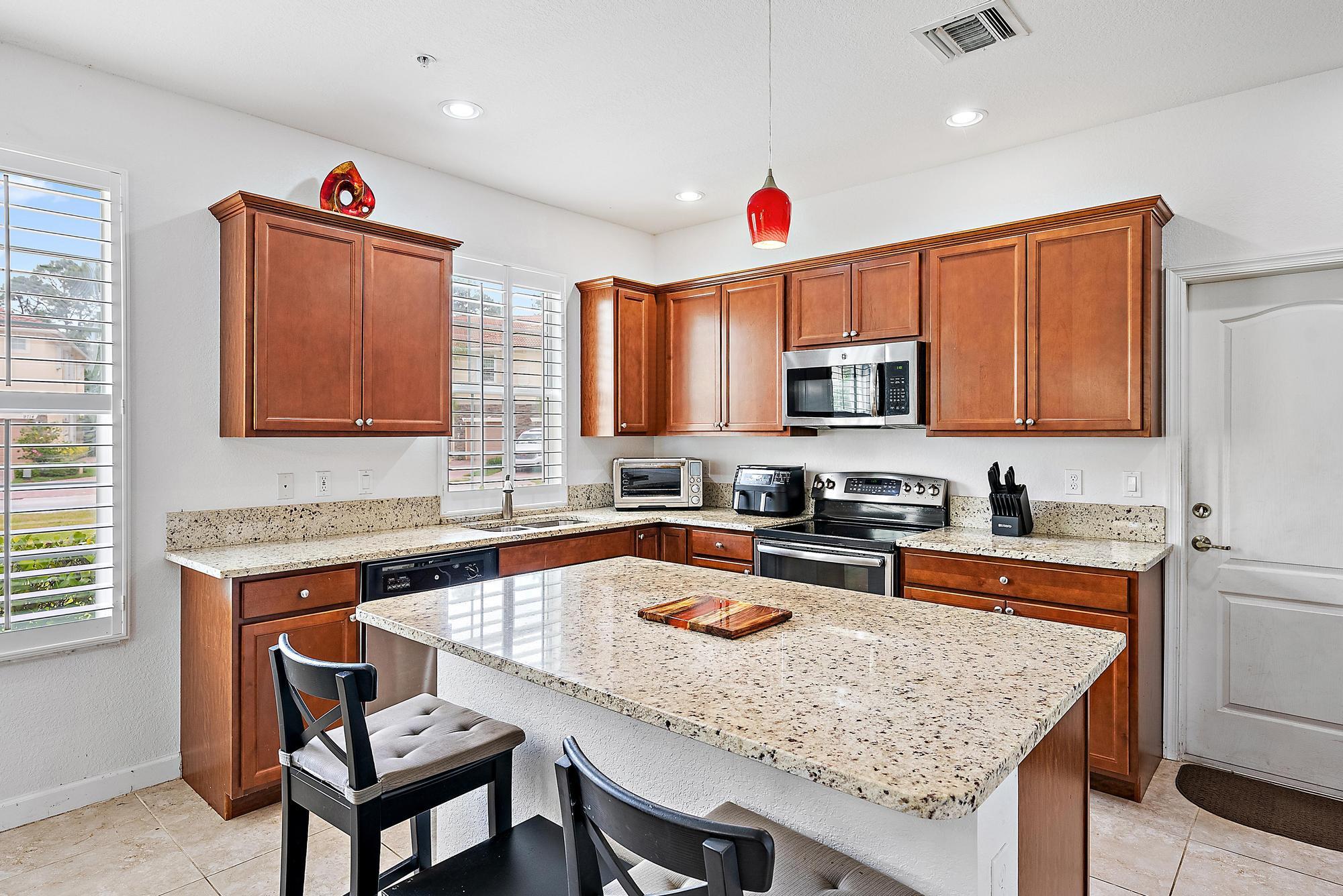 9677 Southwest Purple Martin Way Stuart, FL 34997 - Photo 5 of 29 a kitchen with granite countertop kitchen island stainless steel appliances a sink stove top oven and granite counter tops