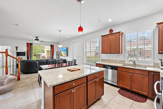 a kitchen with granite countertop a sink dishwasher a dining table and chairs with wooden floor