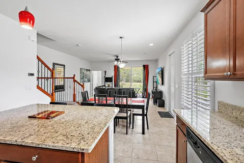 a kitchen with stainless steel appliances kitchen island granite countertop a table chairs in it and wooden floors