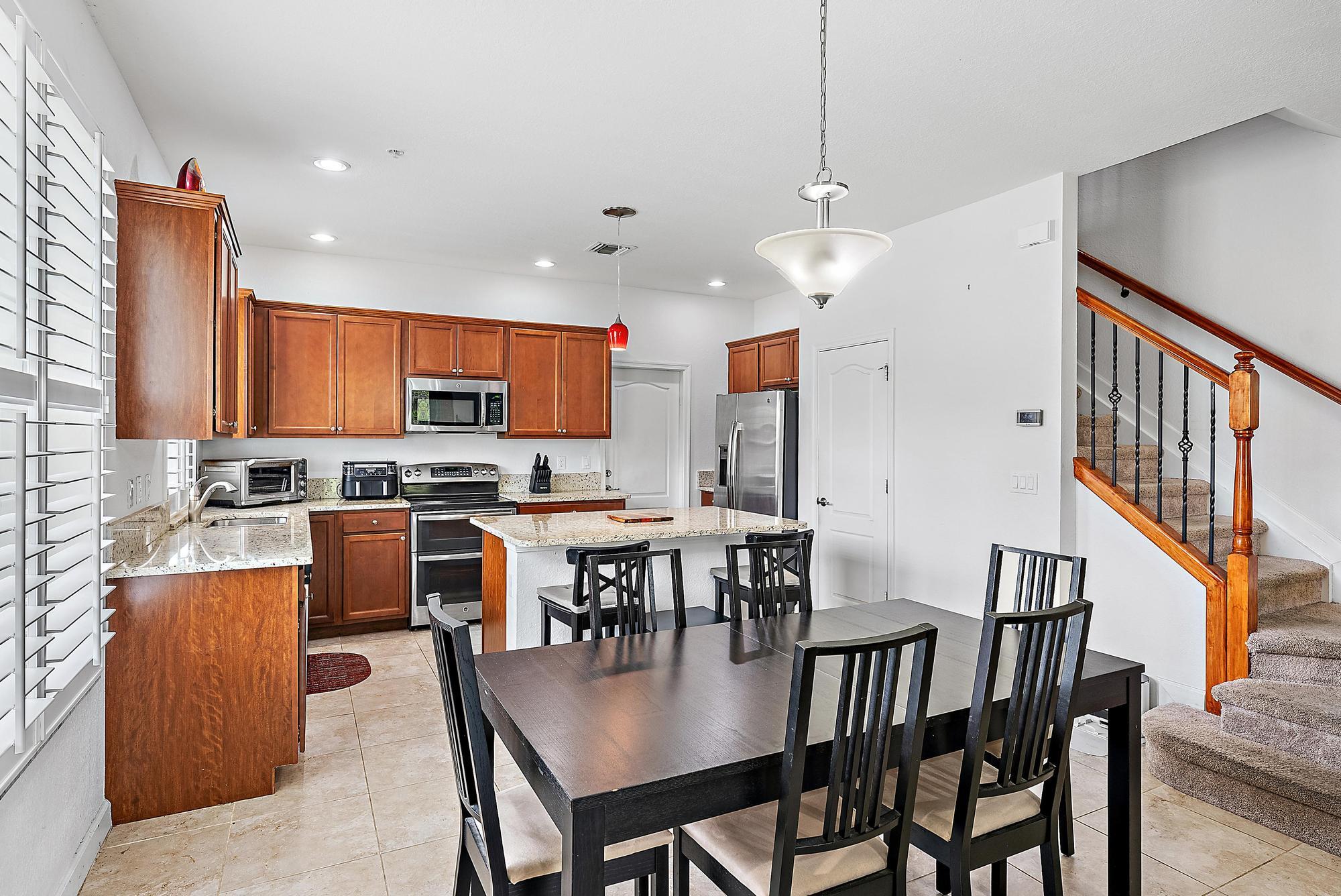 9677 Southwest Purple Martin Way Stuart, FL 34997 - Photo 8 of 29 a open kitchen with stainless steel appliances granite countertop a stove a refrigerator a kitchen island a dining table and chairs