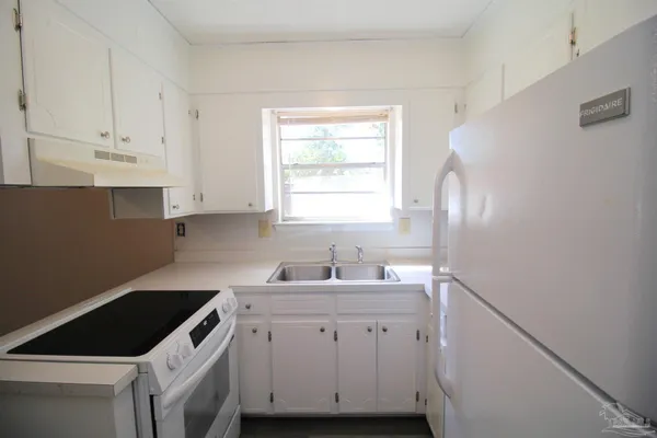 a kitchen with cabinets appliances a sink and a window