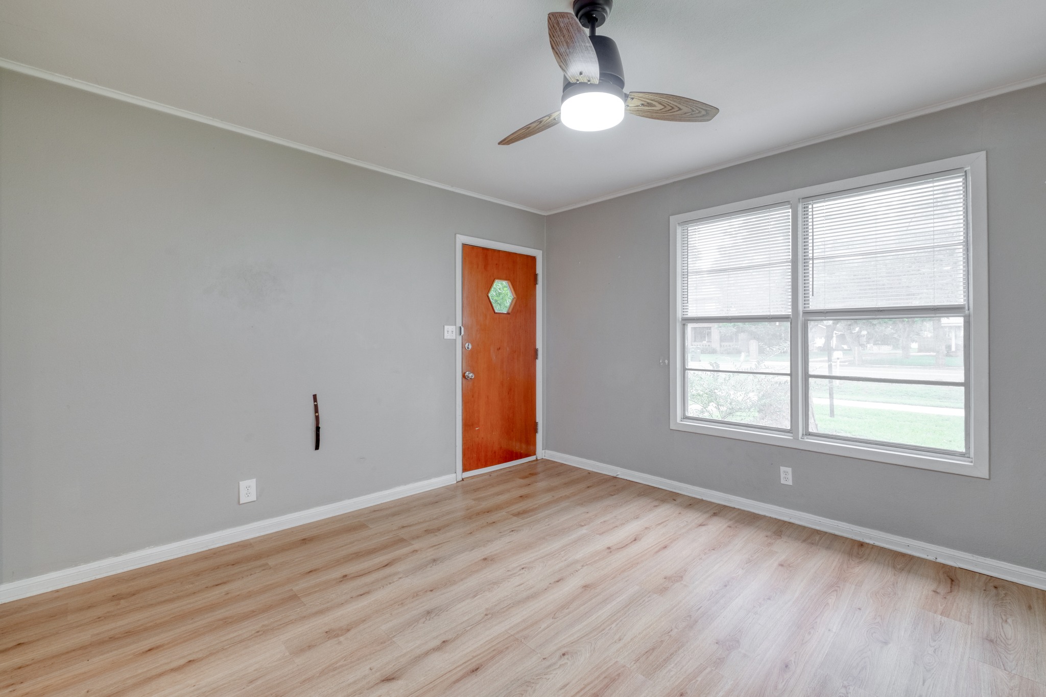707 North Main Street Elgin, TX 78621 - Photo 15 of 21 Living room view toward the front entry door with wood look flooring, ceiling fan and windows for great natural lighting