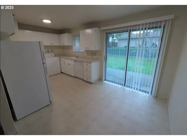 a open kitchen with white cabinets and a refrigerator