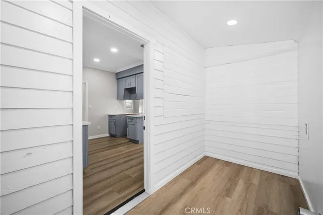 a view of a hallway with wooden floor and a bathroom
