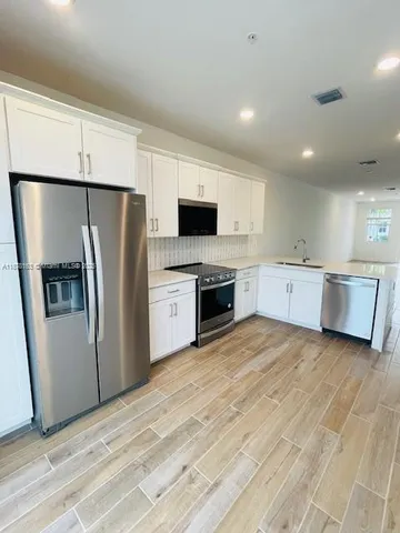 a large kitchen with a refrigerator and a stove top oven