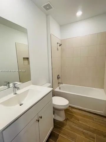 a bathroom with a sink a toilet a mirror a bathtub and shower