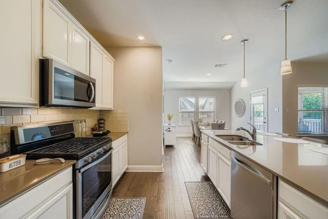 a kitchen with stainless steel appliances a sink a stove top oven a refrigerator a sink and dishwasher