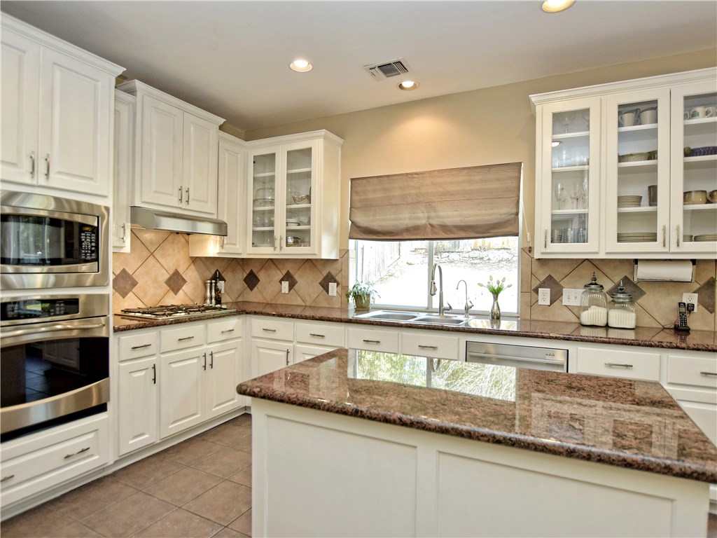 2744 Grimes Ranch Road Austin, TX 78732 - Photo 1 of 1 a kitchen with granite countertop white cabinets and white stainless steel appliances