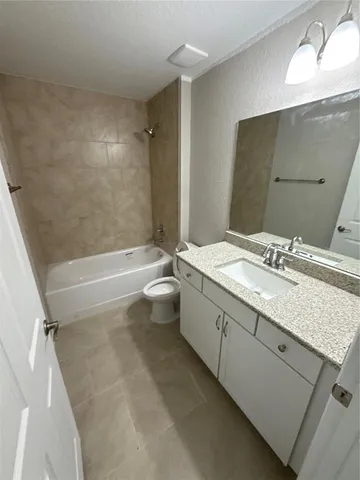 a bathroom with a granite countertop sink a toilet and bathtub