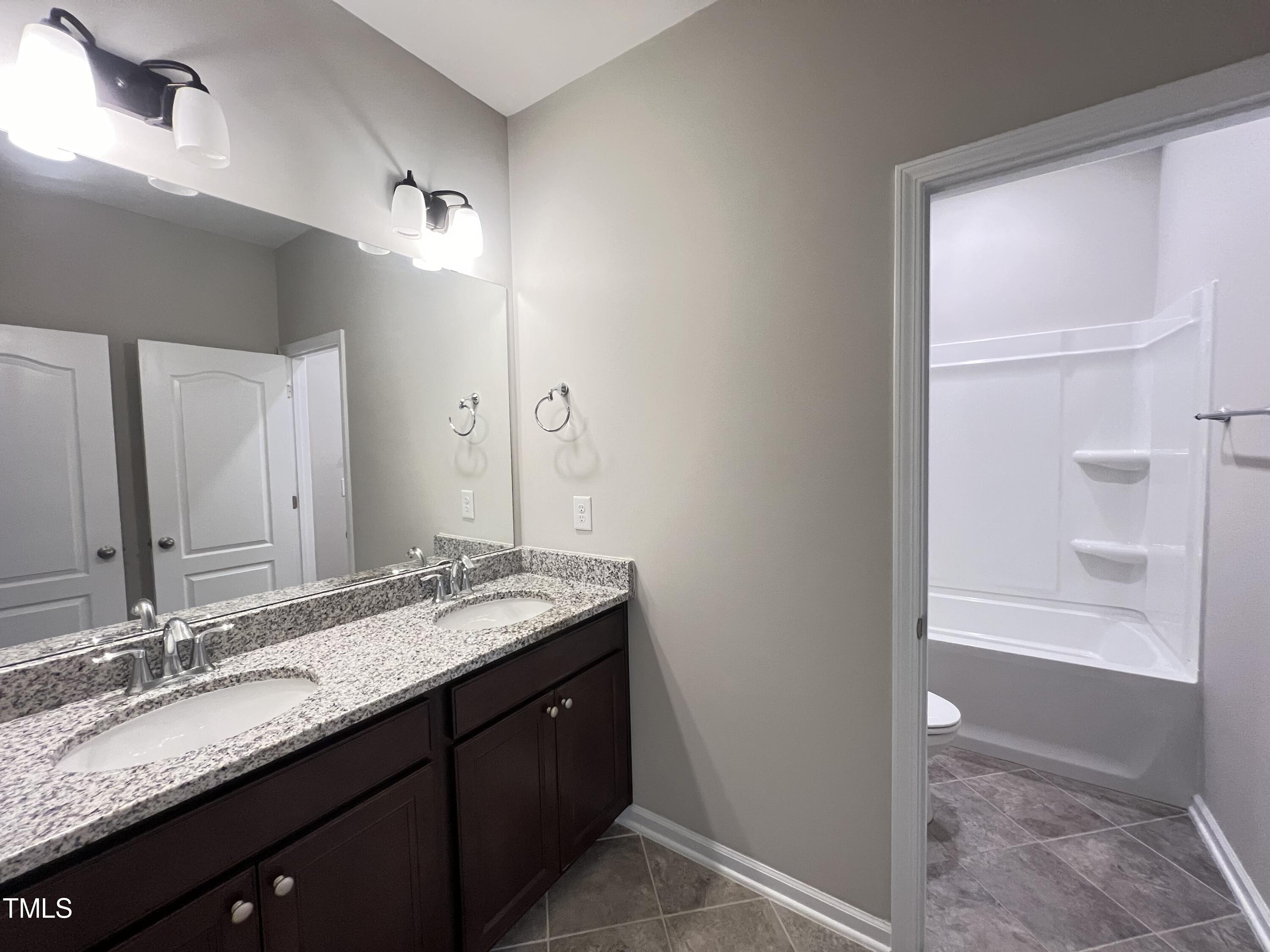 3385 Lovage Drive Apex, NC 27502 - Photo 17 of 19 a bathroom with a granite countertop sink and a mirror