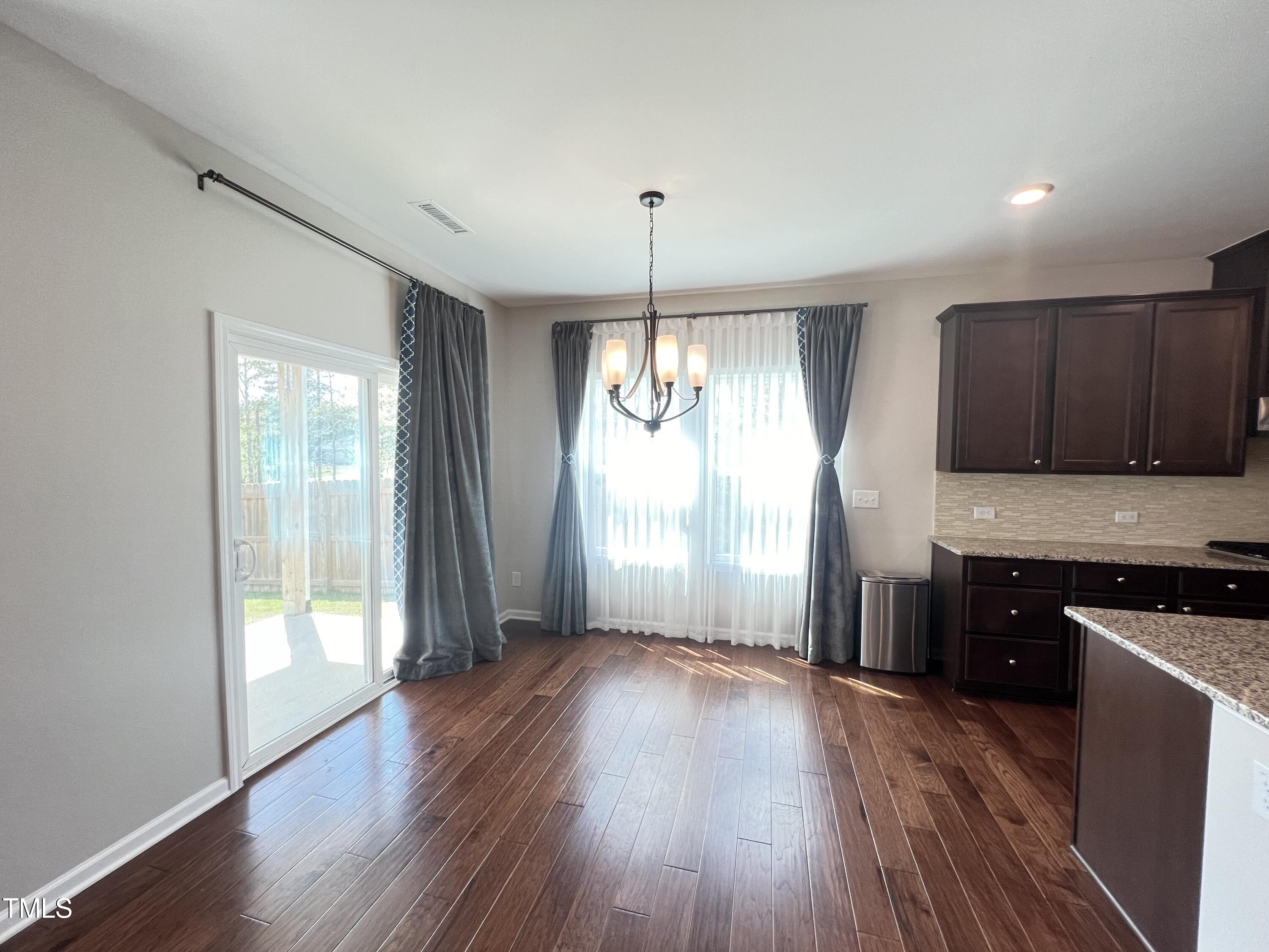3385 Lovage Drive Apex, NC 27502 - Photo 4 of 19 a kitchen with granite countertop wooden floors and white cabinets