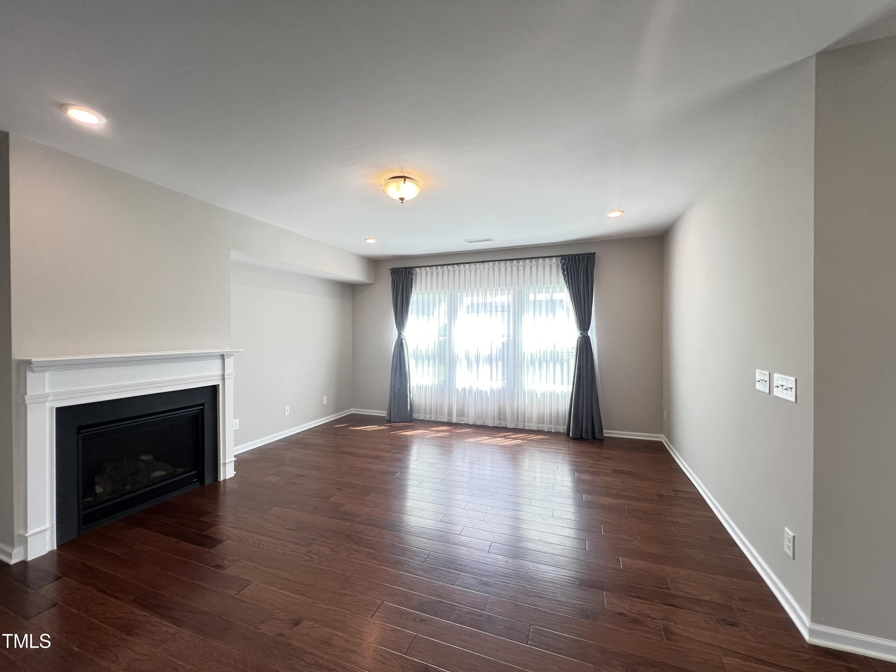 3385 Lovage Drive Apex, NC 27502 - Photo 5 of 19 an empty room with wooden floor fireplace and windows