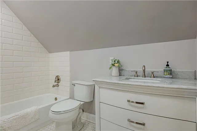 a bathroom with a granite countertop toilet a sink a mirror and bathtub