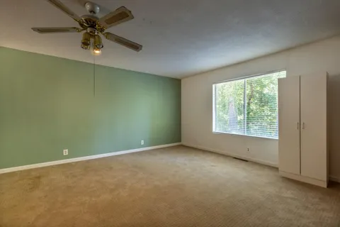 an empty room with a window and a fan