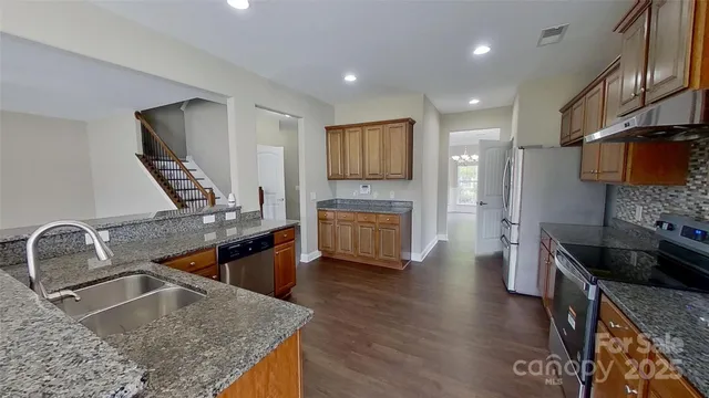 a kitchen with stainless steel appliances granite countertop a sink stove and refrigerator