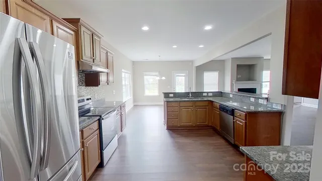 a large kitchen with stainless steel appliances granite countertop a refrigerator a stove and a sink