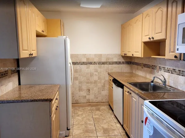 a kitchen with granite countertop a sink a stove and a refrigerator