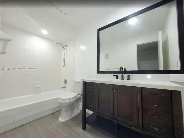 a bathroom with a double vanity sink and mirror with toilet