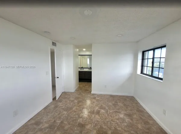 an empty room with windows and cabinet