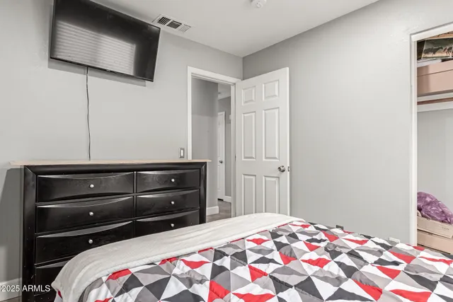 a bedroom with a bed and a flat tv screen on dresser