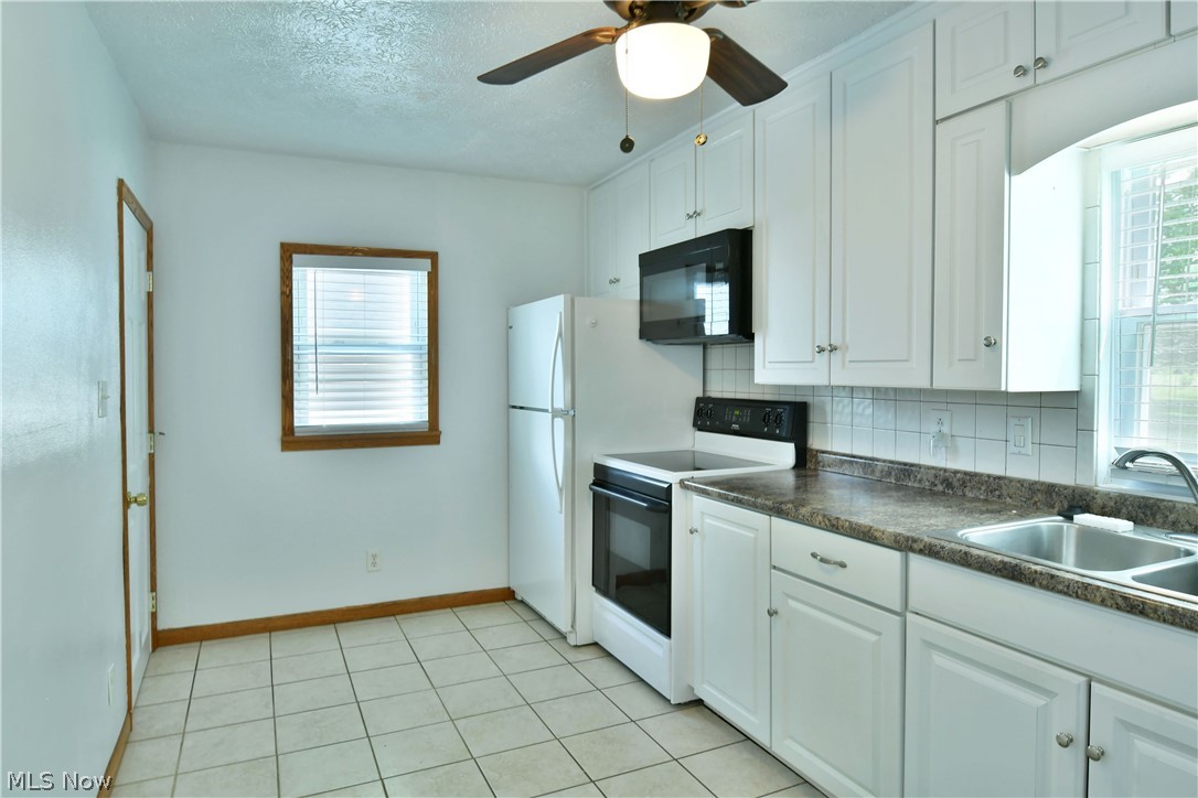 1071 Niles Vienna Road Vienna, OH 44473 - Photo 10 of 35 Kitchen with backsplash, white cabinets, ceiling fan, and white appliances