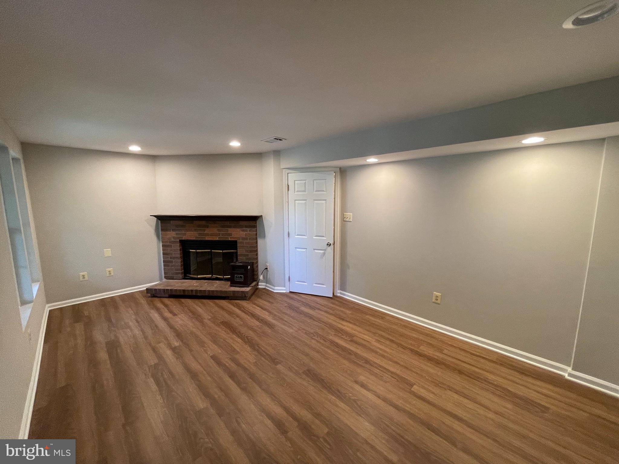 21924 Greentree Terrace Sterling, VA 20164 - Photo 15 of 29 an empty room with wooden floor and fireplace