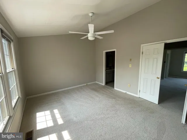 an empty room with windows and fan