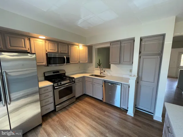a kitchen with a sink wooden floor and stainless steel appliances