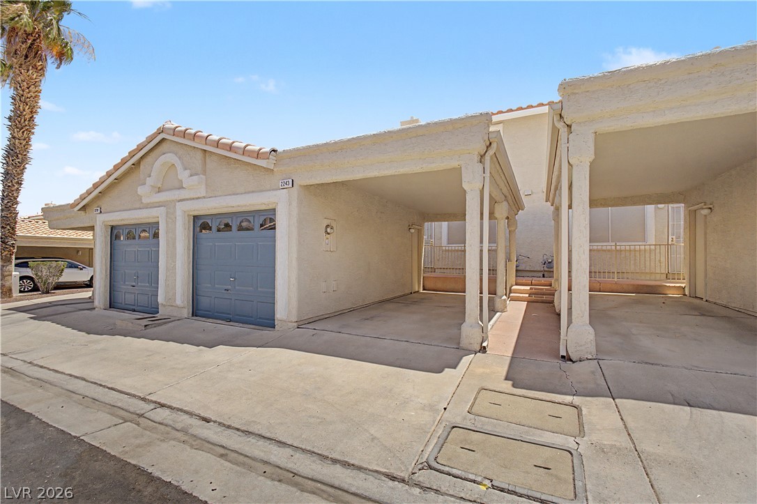 2243 Rugged Mesa Drive Laughlin, NV 89029 - Photo 27 of 32 A well-maintained stucco facade with a two-car garage and adjacent covered parking.