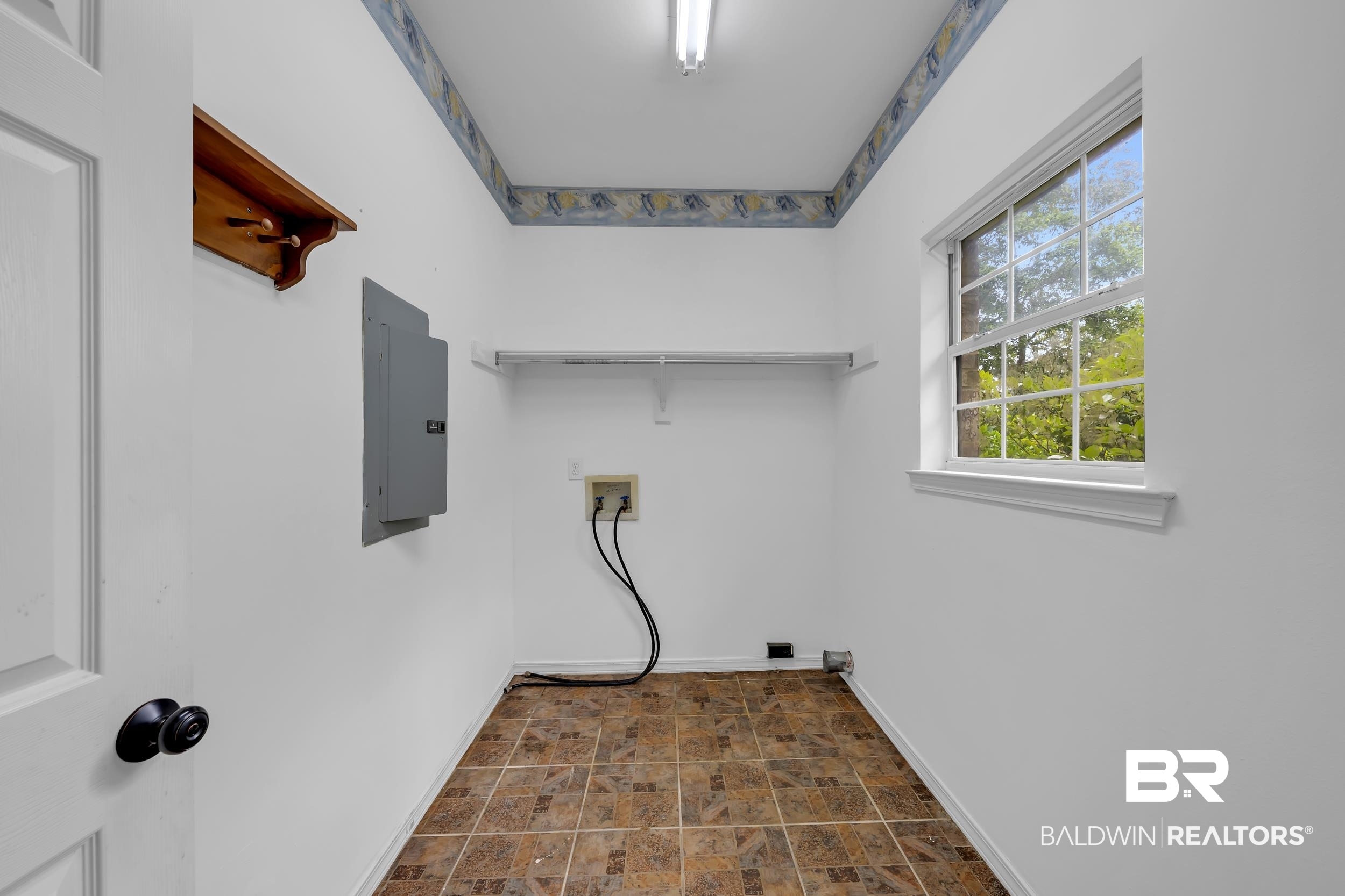 14960 Howells Ferry Road Wilmer, AL 36587 - Photo 19 of 22 Dedicated utility space featuring tile flooring, a window with natural light, integrated shelving, and wall-mounted electrical panel