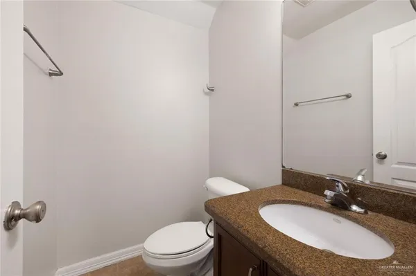 a bathroom with a granite countertop toilet a sink and mirror