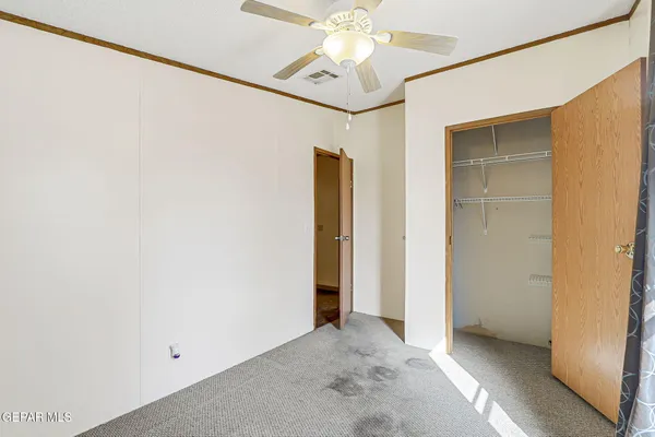 an empty room with windows and ceiling fan
