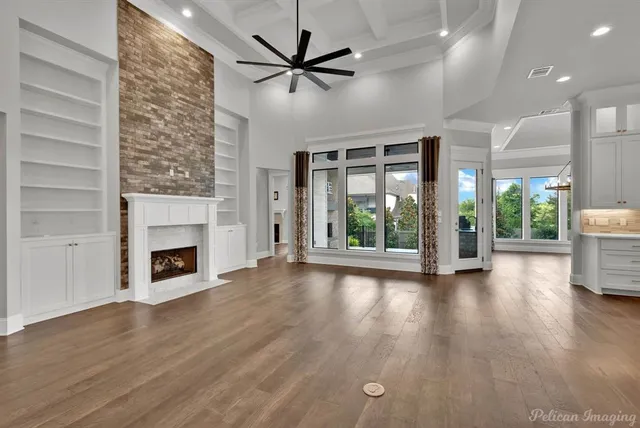 a view of a livingroom with wooden floor a fireplace and windows